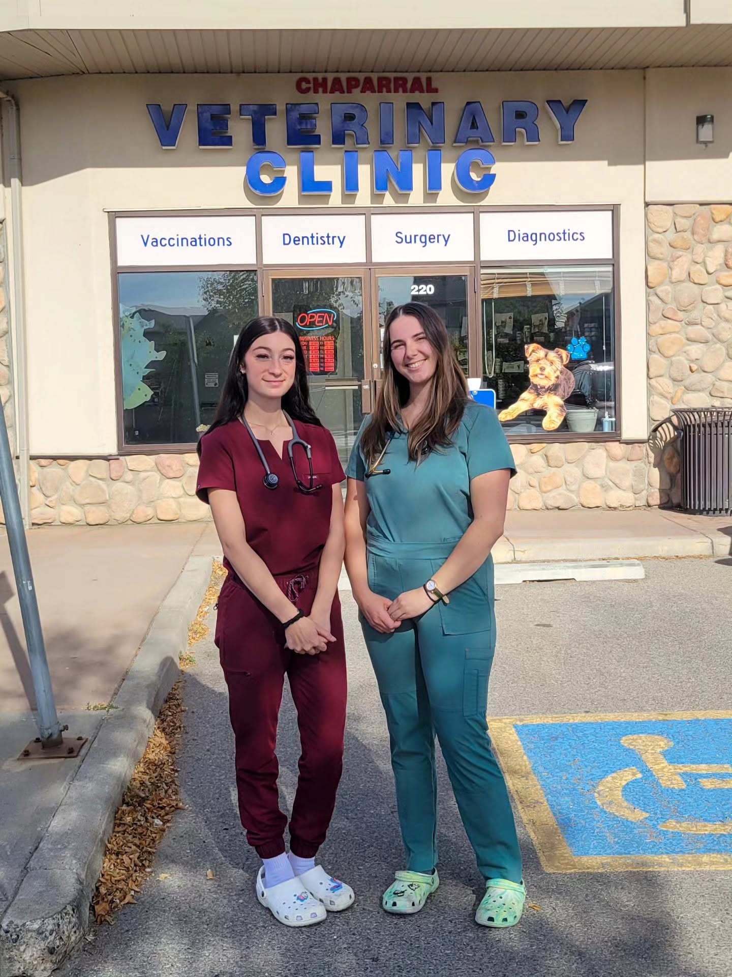 Two Chaparral Veterinary Clinic team members in scrubs outside the clinic entrance at 803 Chaparral Drive SE